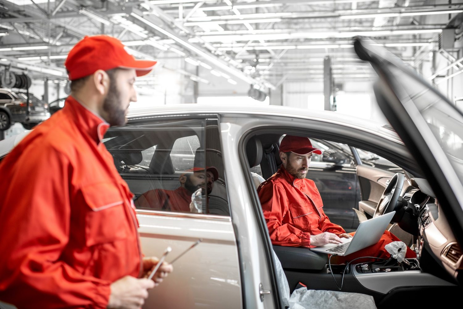 mechanics diagnosing car with computer at the car service